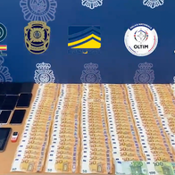 Money, phones and laptops spread out on a table that Police have confiscated.