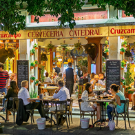 People sat at tables on a pavement outside a traditional Spanish bar.