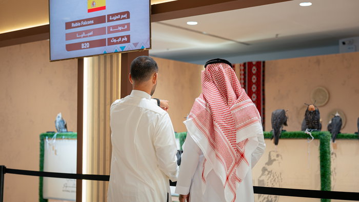 2 Arabs looking at falcons on display at a farm