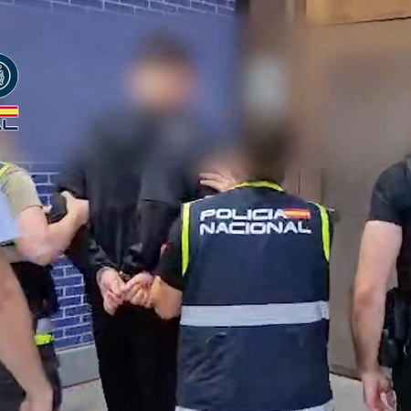 Spanish national police walk the Swedish fugitive into custody.