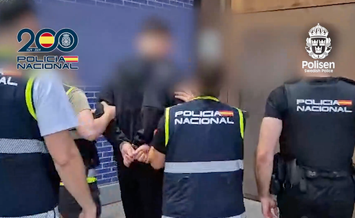 Spanish national police walk the Swedish fugitive into custody.