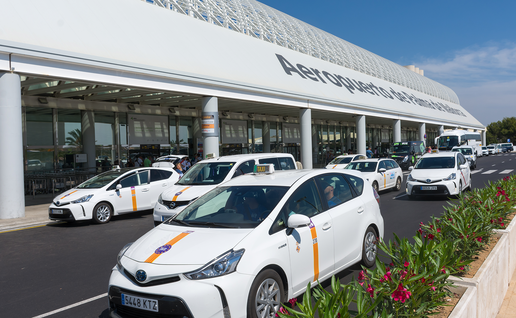 White taxis parked in a row outside the Aeropuerto de Palma de Mallorca terminal building.