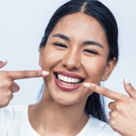 Picture of a young girl pointing to her lovely smile with perfect teeth