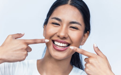 Picture of a young girl pointing to her lovely smile with perfect teeth