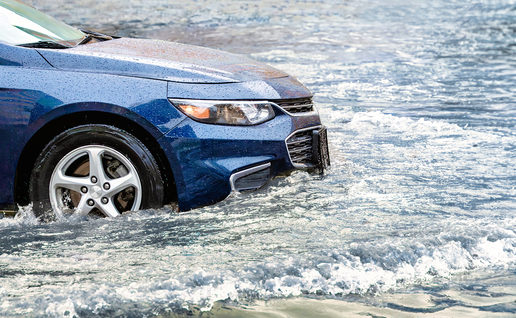 A car driving through floodwater on a road