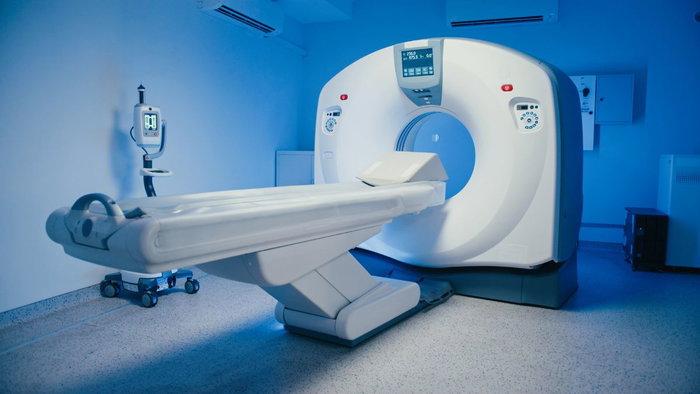A modern white MRI scanner machine in a brightly lit blue medical room, used for advanced prostate cancer diagnostic imaging.