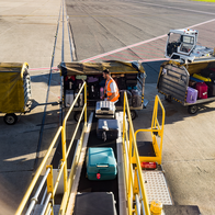 View from the window of a plane of suitcases being loaded onto an aircraft.