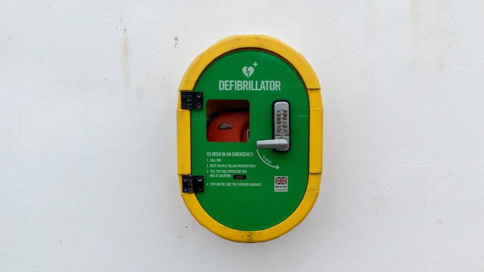 An automated external defibrillator (AED) in an emergency box mounted outdoors, symbolizing public access to lifesaving medical equipment.