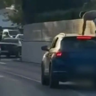 Despite the fast-moving traffic, a person was spotted hitching a ride on the roof of a car
