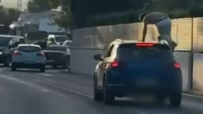 Despite the fast-moving traffic, a person was spotted hitching a ride on the roof of a car
