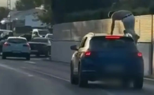 Despite the fast-moving traffic, a person was spotted hitching a ride on the roof of a car