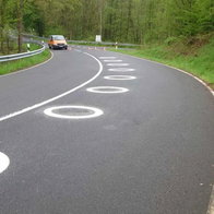 White circles painted on the curve of the road to improve motorcycle safety