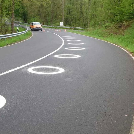 White circles painted on the curve of the road to improve motorcycle safety