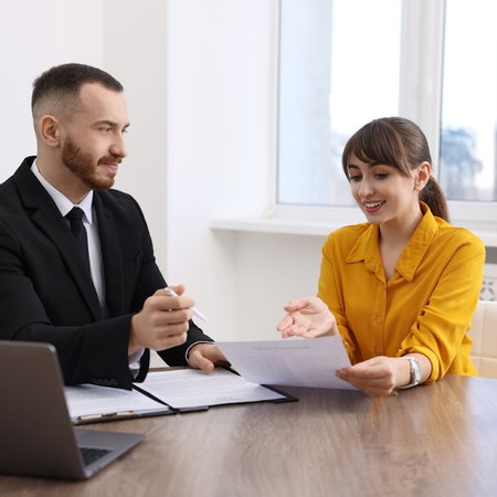 Woman having meeting with professional lawyer at wooden desk indoors