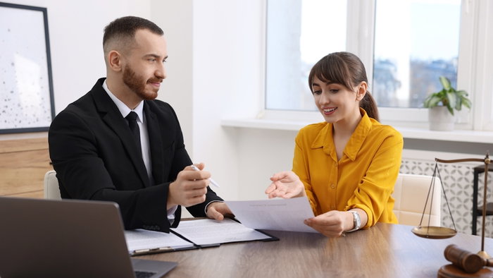 Woman having meeting with professional lawyer at wooden desk indoors