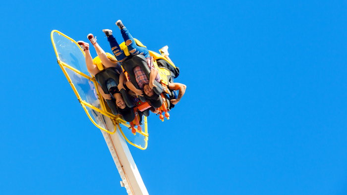Two young women are upside down while riding a fair ride.
