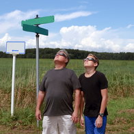 two people looking up at a solar eclipse with protective glasses