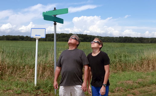 two people looking up at a solar eclipse with protective glasses