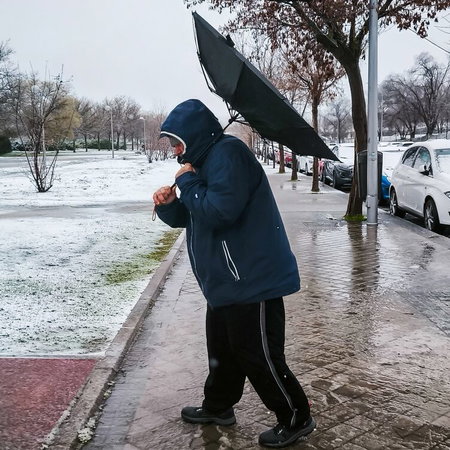 Man in snow and wind with umbrella inside out