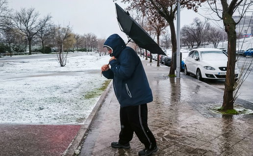 Man in snow and wind with umbrella inside out