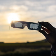 Hand holding solar eclipse glasses during the total eclipse in Spain