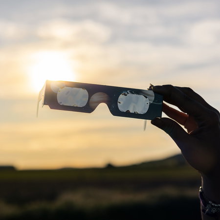 Hand holding solar eclipse glasses during the total eclipse in Spain