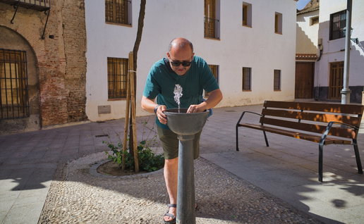 Man drinking from fountain in Spanish village on hot day