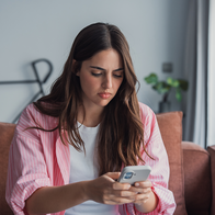 Young woman looking worryingly at her phone.