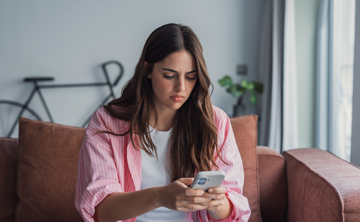 Young woman looking worryingly at her phone.