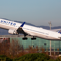 A United Airlines flight takes off in front of the Barcelona Airport building.