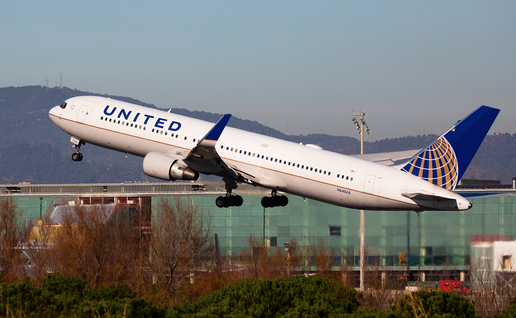 A United Airlines flight takes off in front of the Barcelona Airport building.