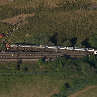 Aerial view of a derailed train with emergency responders on rural tracks