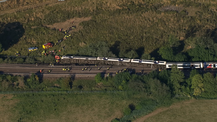 Aerial view of a derailed train with emergency responders on rural tracks