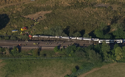 Aerial view of a derailed train with emergency responders on rural tracks