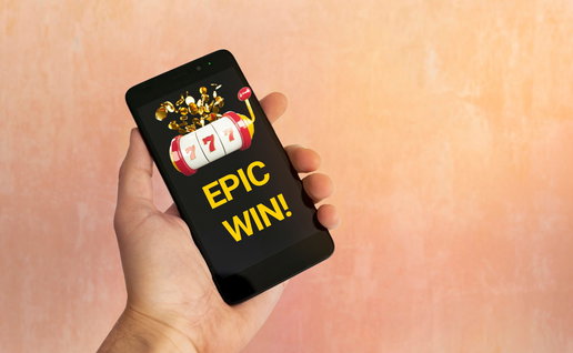 Man's hand holding a mobile phone with Epic win on screen from online casino