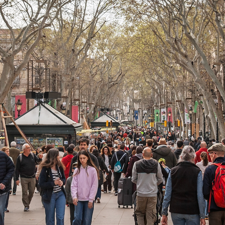 Pedestrians walking along a busy, tree-lined street in Barcelona.