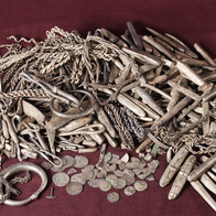 Silver ingots, coin fragments and jewellery from a Viking-era hoard laid out on a dark surface