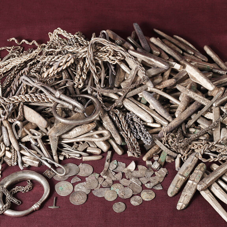 Silver ingots, coin fragments and jewellery from a Viking-era hoard laid out on a dark surface