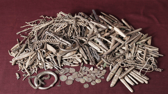Silver ingots, coin fragments and jewellery from a Viking-era hoard laid out on a dark surface