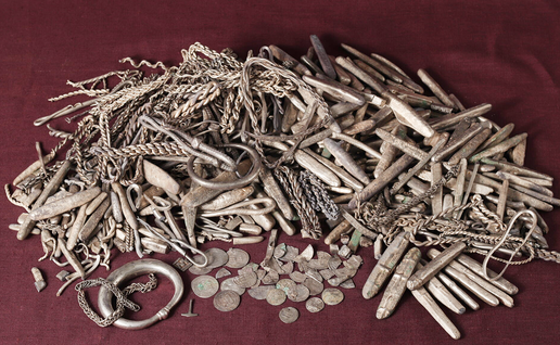 Silver ingots, coin fragments and jewellery from a Viking-era hoard laid out on a dark surface