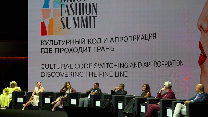 View of the stage at the Fashion summit with the speakers sat on the stage