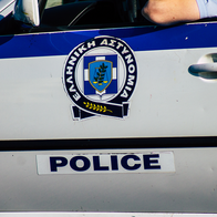 A Greek Police patrol car, with an officer resting his arm on the open window.