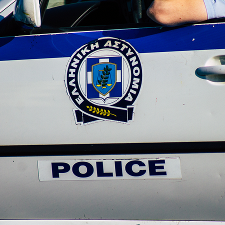 A Greek Police patrol car, with an officer resting his arm on the open window.