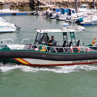 Guardia Civil boat passing through coastal port.