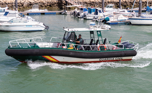 Guardia Civil boat passing through coastal port.