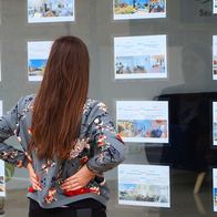 A woman views property listings displayed in an estate agency window in Spain.