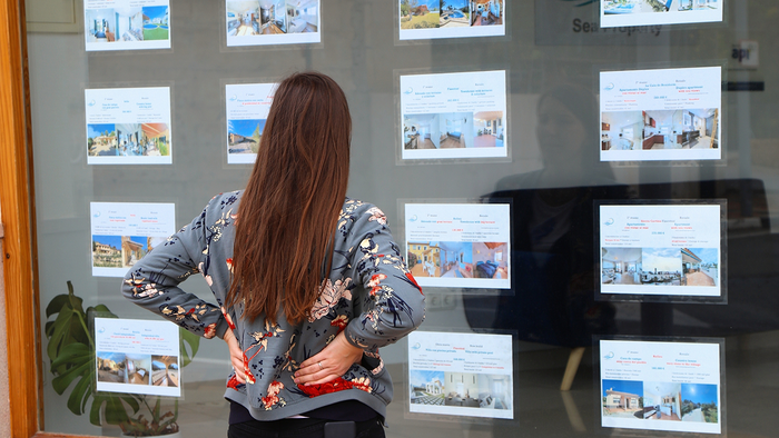 A woman views property listings displayed in an estate agency window in Spain.