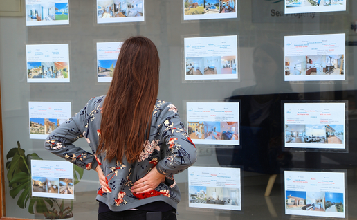 A woman views property listings displayed in an estate agency window in Spain.