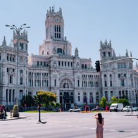 View of Palacio de Cibeles in Madrid, with a woman in the square looking at the building