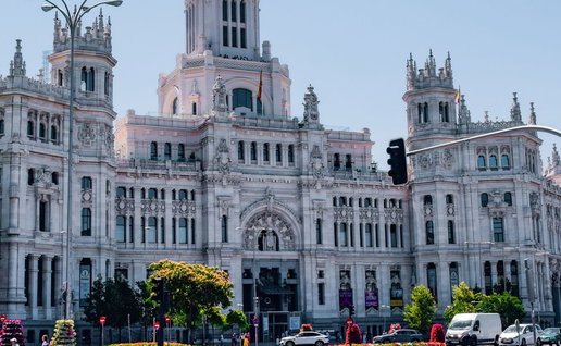 View of Palacio de Cibeles in Madrid, with a woman in the square looking at the building